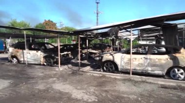 Kül ve çamur kaplı yanmış cesetlerde bükülmüş metal ve erimiş yapılar görülüyor. Arabanın içi mahvolmuş. Askeri çatışma ve bombardıman sonucu. Yıkılmış otopark.