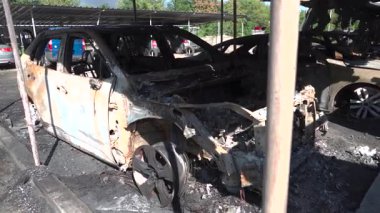 Kül ve çamur kaplı yanmış cesetlerde bükülmüş metal ve erimiş yapılar görülüyor. Arabanın içi mahvolmuş. Askeri çatışma ve bombardıman sonucu. Yıkılmış otopark.