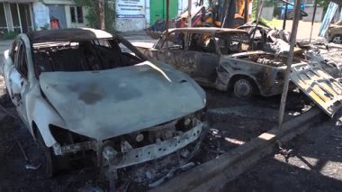 Kül ve çamur kaplı yanmış cesetlerde bükülmüş metal ve erimiş yapılar görülüyor. Arabanın içi mahvolmuş. Askeri çatışma ve bombardıman sonucu. Yıkılmış otopark.