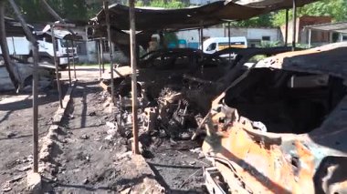 Kül ve çamur kaplı yanmış cesetlerde bükülmüş metal ve erimiş yapılar görülüyor. Arabanın içi mahvolmuş. Askeri çatışma ve bombardıman sonucu. Yıkılmış otopark.