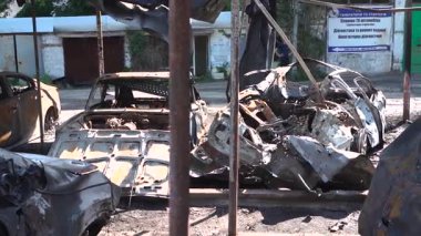 Kül ve çamur kaplı yanmış cesetlerde bükülmüş metal ve erimiş yapılar görülüyor. Arabanın içi mahvolmuş. Askeri çatışma ve bombardıman sonucu. Yıkılmış otopark.