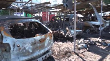 Kül ve çamur kaplı yanmış cesetlerde bükülmüş metal ve erimiş yapılar görülüyor. Arabanın içi mahvolmuş. Askeri çatışma ve bombardıman sonucu. Yıkılmış otopark.