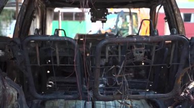 Kül ve çamur kaplı yanmış cesetlerde bükülmüş metal ve erimiş yapılar görülüyor. Arabanın içi mahvolmuş. Askeri çatışma ve bombardıman sonucu. Yıkılmış otopark.