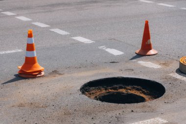 Şehir caddesinde bir iş yeri, yol yüzeyi onarımı ve rögar kapağı kurulumu. Yakın plan hazırlanmış bir delik. Resim, şehrin altyapısını korumak için yapılan çalışmaların safhalarını vurguluyor..