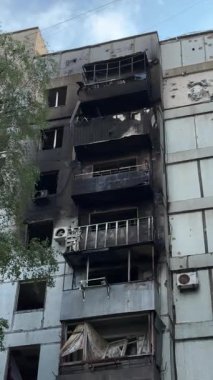 A damaged residential building with burnt-out balconies after shelling or fire. Broken windows and collapsed balcony structures are visible, the consequences of a conflict of damage.