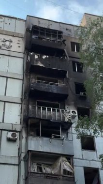 A damaged residential building with burnt-out balconies after shelling or fire. Broken windows and collapsed balcony structures are visible, the consequences of a conflict of damage.