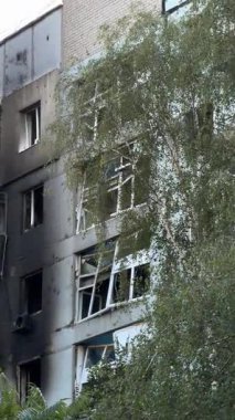 A damaged residential building with burnt-out balconies after shelling or fire. Broken windows and collapsed balcony structures are visible, the consequences of a conflict of damage.