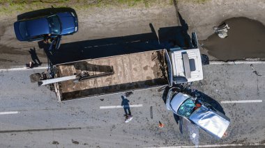 Aerial view of a serious traffic accident. A flatbed truck collided with a passenger car on a two-lane road. Severe damage to both vehicles is visible. Concept of hazard, insurance, and safety.
