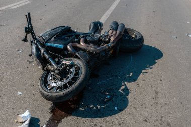 Kaza yapan bir motosiklet (motosiklet), bir trafik kazası sonrasında asfaltta yan yatar. Bir kazadan sonra yol kenarında duruyor. Farlar ve gidonlar kırılmış. Tehlike ve sigorta kavramı.