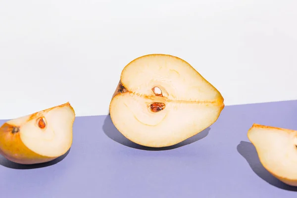 Creative layout made of raw sliced pears on white and violet background. Minimal style. Healthy food ingredient concept. Still life composition
