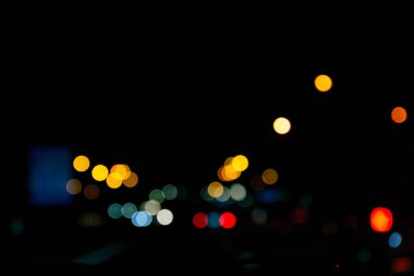 Arabanın ön camından görünen odaksız gece lambaları. Şehir soyut bokeh arkaplanı.
