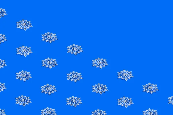 Parlak Mavi Arka Planda Beyaz Kar Tanelerinden Oluşan Kış Deseni — Stok fotoğraf