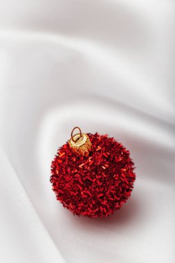 Kırmızı süs eşyası ve beyaz ipek çarşaftan yapılmış yaratıcı bir arka plan. Asgari tarz kompozisyon. Yılbaşı konsepti