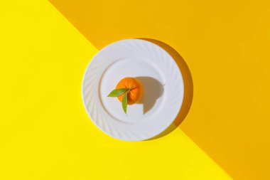 Beyaz tabakta taze turuncu mandalinadan yapılmış minimal bir kompozisyon. Yaz tatili konsepti. Üst Manzara. Düz yatıyordu