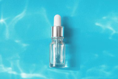 Şeffaf cam serumdan yapılmış, pipetli, kolajenli ya da hyaluronik asitli ya da mavi su arka planında sıçramalı gerekli yağlı minimum karışım. Kozmetik kaplıca tıbbi cilt bakım konsepti.