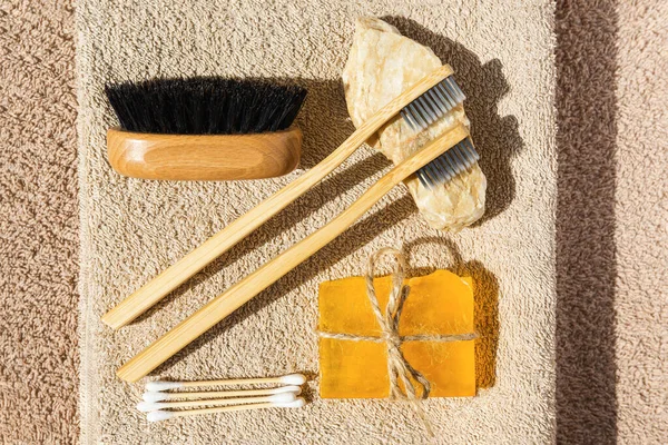 Set of eco cosmetic products and tools. Handmade soap, bamboo toothbrush, natural wooden brush and ear buds on  beige bath towel. Plastic free, zero waste, sustainable lifestyle concept.