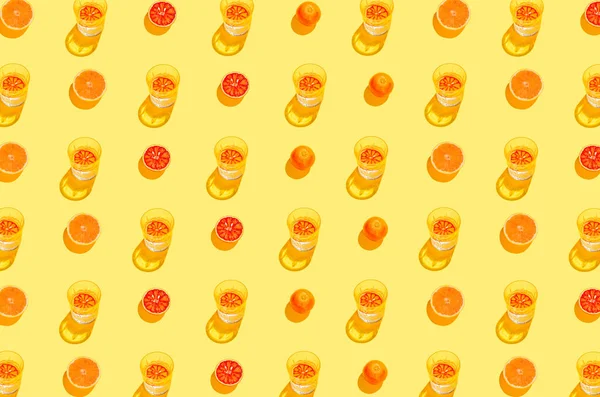 黄色の背景にレモネードや水でスライスされた血オレンジとガラスで作られた創造的なパターン 夏の果物とリフレッシュの概念 ミニマルなスタイル トップ表示 — ストック写真