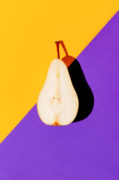Creative layout made of raw sliced pear on bright violet and orange geometric background with shadow. Minimal style. Healthy food ingredient concept. Top view. Flat lay