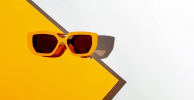 Turuncu ve beyaz güneşli arka planda son moda güneş gözlüklerinden oluşan minimal biçim kompozisyonu
