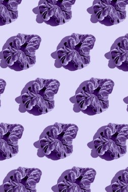 Pastel arka planda mor saç bantlarından yapılmış yaratıcı desen. Asgari biçim