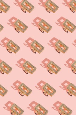 Pastel pembe arka planda gölgeli altın saç tokasından yapılmış yaratıcı desen