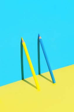 Güneşli arka planda gölgeli sarı ve mavi kalemlerden oluşan minimal bir kompozisyon. Okul konseptine dönelim.