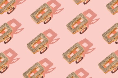 Pastel pembe arka planda gölgeli altın saç tokasından yapılmış yaratıcı desen