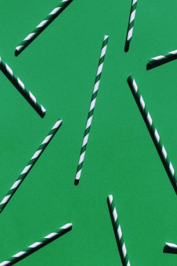 Yeşil arkaplandaki kağıt kamışlardan oluşan minimum biçim bileşimi. Şenlik ve parti konsepti. Üst Manzara. Düz yatıyordu