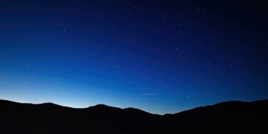 Parlak Samanyolu Galaksisi 'nin görkemli dağların üzerinde sergilendiği göz kamaştırıcı gece manzarası. Doğa, astronomi ve macera temaları için mükemmel nefes kesici yıldızlı bir gökyüzü..