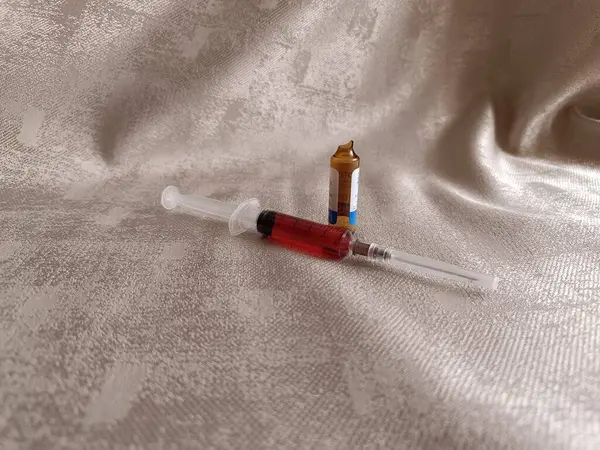Beyaz zemin üzerinde kırmızı ve mavi sıvı olan şırınga.
