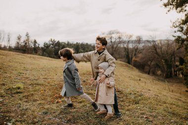 Çocuklar oynuyor, gülümsüyor, sonbahar günü parkta vakit geçiriyorlar..