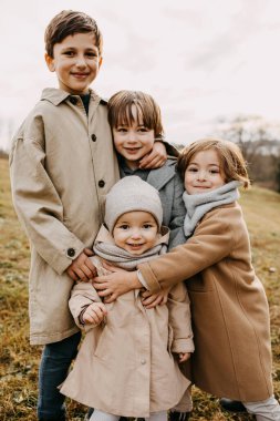 Closeup of brothers hugging little sister, smiling, outdoors on autumn day. clipart