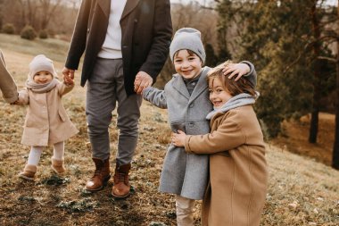 Aile sonbahar günü dışarı çıkıyor, birlikte eğleniyor. Çocuklar sarılıyor ve gülüyor..