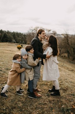 Büyük bir aile dışarıda eğleniyor. Çocuklar ailelere sarılıyor..