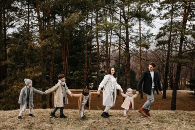 6 kişilik büyük bir aile bir ormanda el ele tutuşarak yürüyor..