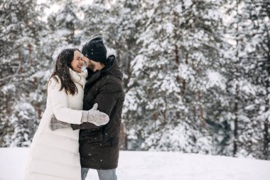 Mutlu çift dışarıda vakit geçiriyor, soğuk bir kış gününde sarılıyor ve gülümsüyor..