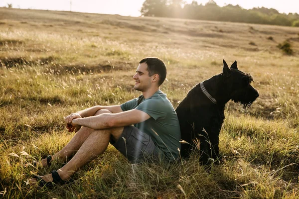 Junger Mann Sitzt Auf Einem Feld Neben Einem Großen Schwarzen — Stockfoto