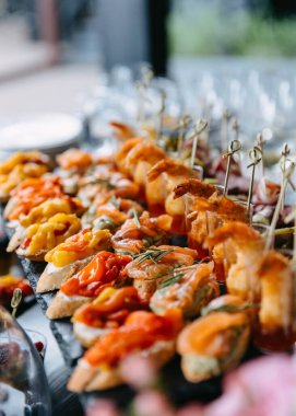 Closeup of different snacks at a party. Mini sandwiches on a fourchette table.