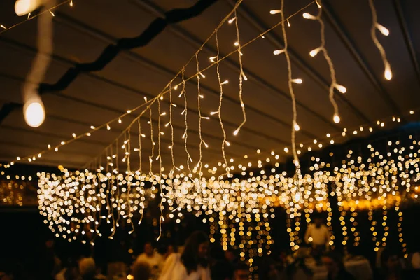 String led fairy lights in warm yellow tone at a party at night.