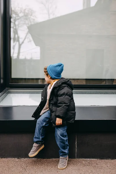 幼児男の子 ガラスの壁の背景に座って — ストック写真
