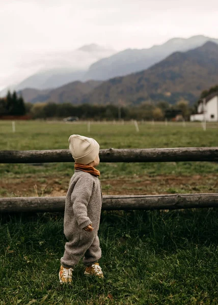 寒い秋の朝 山の上に柵のある田舎の緑の芝生の上に立つ子供 — ストック写真