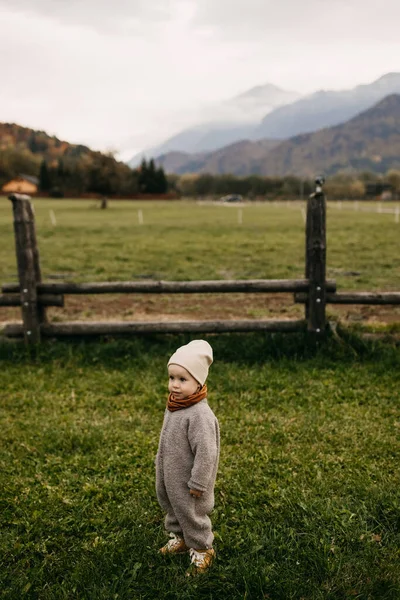 Dziecko Stojące Zielonym Trawniku Farmie Drewnianym Płotem Tle Gór — Zdjęcie stockowe