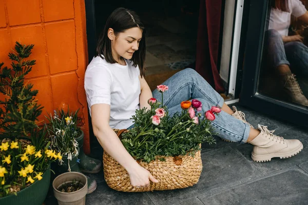在花店工作的花匠女人照顾我们的花 把它们放在一个大篮子里 — 图库照片