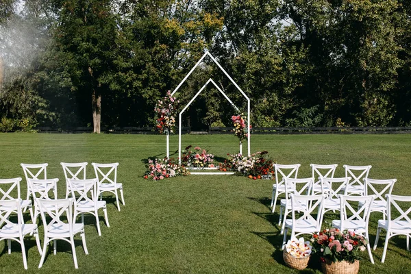 Ceremonia Ślubna Łukiem Ozdobionym Kwiatami Białymi Drewnianymi Krzesłami Umieszczonymi Zielonej — Zdjęcie stockowe
