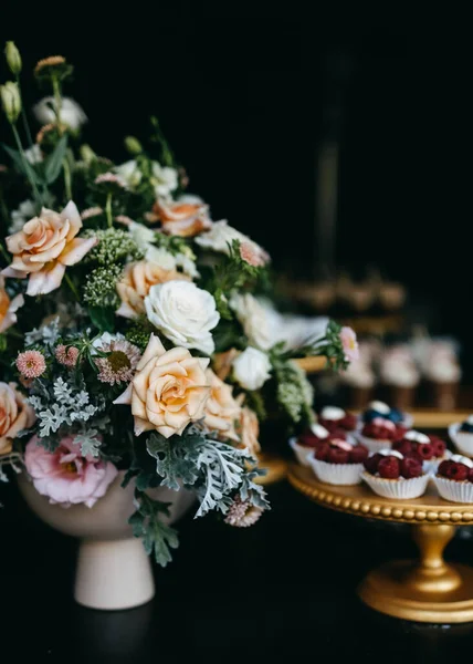 結婚式のキャンディーバーでバラで作られた大きな中心部 ブルーベリーカップケーキと異なる手作りのデザートと甘いテーブル — ストック写真