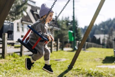 Güneşli bir bahar gününde, çocuk salıncakta gülüyor..