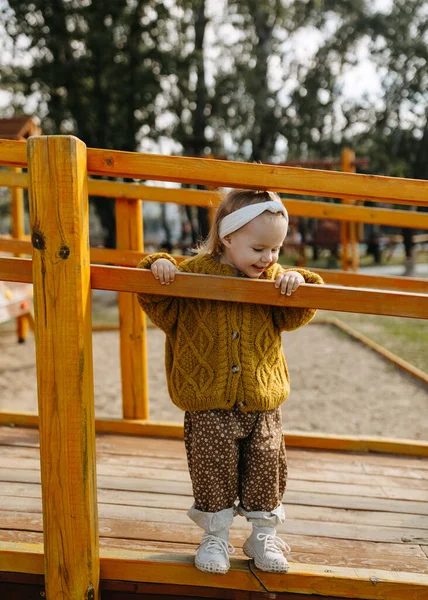 Mała Szczęśliwa Dziewczynka Drewnianym Placu Zabaw Ubrana Musztardowy Sweter — Zdjęcie stockowe