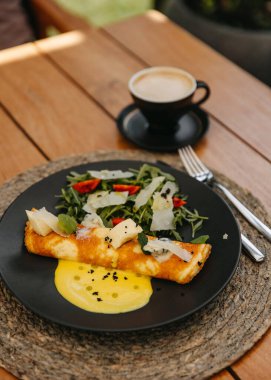 Peynirli omlet ve tabakta salata, bir fincan kahve..