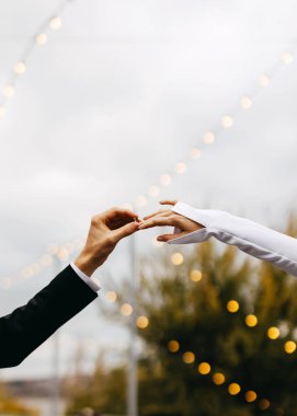 Partneri tarafından nazikçe tutulan zarif bir nişan yüzüğüyle bir gelin eli.