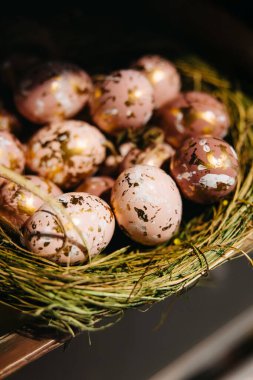 Pembe ve altın benekli Paskalya yumurtaları çimenli bir yuvada.